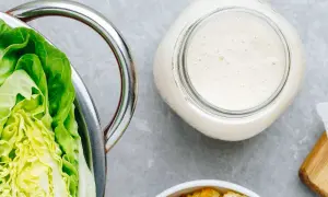 Lechuga romana fresca, un frasco de cremosa salsa césar casera y crutones dorados, listos para una ensalada perfecta.