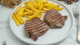 Dos jugosos solomillos de ternera a la parrilla con patatas fritas doradas. Un plato perfecto para disfrutar.