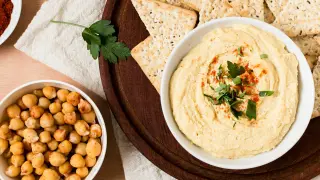 Hummus receta: cremoso dip de garbanzos con pimentón y perejil, acompañado de galletas y garbanzos enteros.