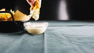 Un trozo de pollo crujiente se sumerge en un cuenco de mayonesa casera, lista para ser disfrutada.
