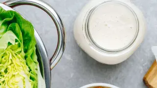 Lechuga romana fresca, un frasco de cremosa salsa césar casera y crutones dorados, listos para una ensalada perfecta.