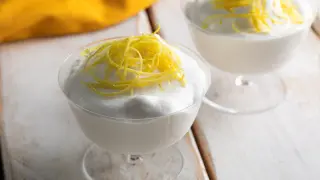 Delicioso mousse de limón receta original, servido en copas y decorado con ralladura de limón.