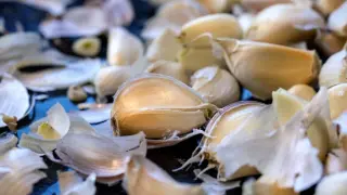 Dientes de ajo pelados y cáscaras esparcidos, listos para revelar sus propiedades del ajo.
