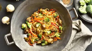 Sabrosos fideos chinos salteados con brócoli, champiñones y pimientos en un wok.