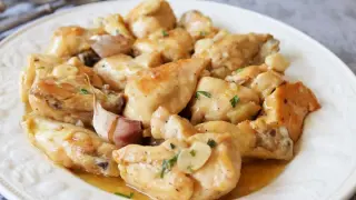 Sabroso pollo al ajillo servido en un plato blanco, con trozos dorados de pollo y abundantes dientes de ajo.