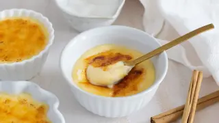 Deliciosa crema catalana recién hecha, con su capa crujiente de caramelo y una cuchara dorada lista para probarla.