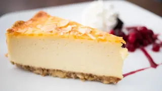 Deliciosa tarta de queso sin horno, cremosa y con almendras tostadas, acompañada de frutos rojos y nata.