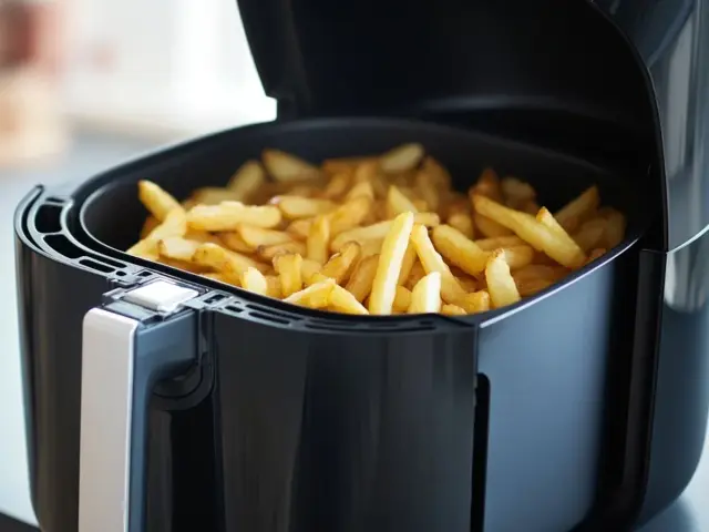 Patatas fritas doradas y crujientes listas para disfrutar, recién salidas de la freidora de aire.