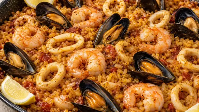 Paella de marisco con gambas, mejillones y anillas de calamar, servida con gajos de limón.